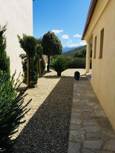 a garden with trees and a walkway next to a building at Villa Carletti à 3min des plages (7pers. - 3ch.) in Oletta