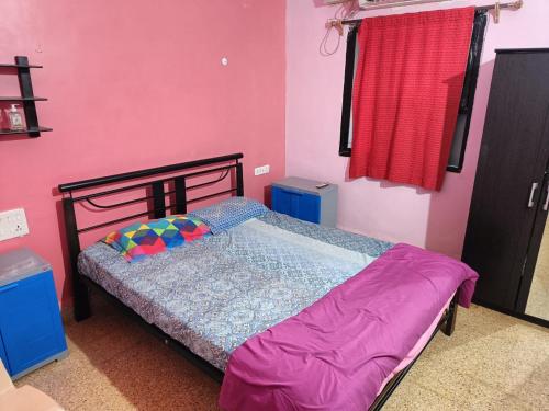 1 dormitorio con 1 cama en una pared de color rosa en Stay at Colva Beach, en Colva