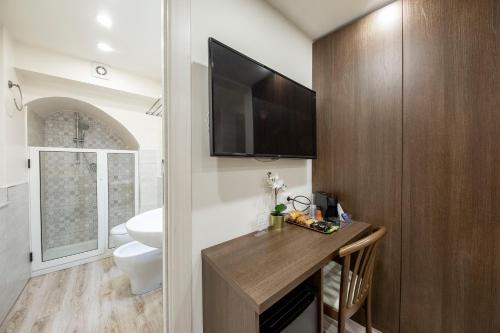 a bathroom with a toilet and a television on the wall at B&B Ambitious in Catania