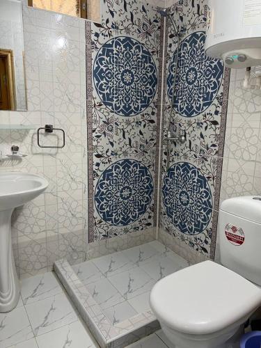 a bathroom with a toilet and a shower with blue and white tiles at Hotel Legende in Samarkand