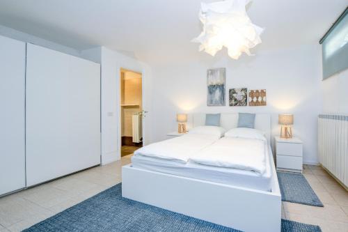 - une chambre blanche avec un lit blanc et un lustre dans l'établissement Casa Dolce Vita, à Toscolano Maderno