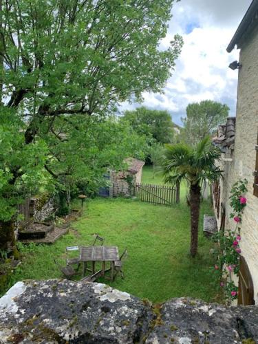 un parc avec un banc et un arbre dans une cour dans l'établissement Gîte du Plaçal, à Aujols