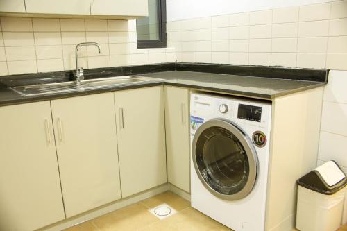 a kitchen with a washing machine and a sink at Infinity Tower Suites WLL in Manama