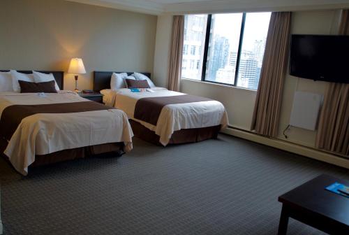 a hotel room with two beds and a flat screen tv at Century Plaza Hotel in Vancouver