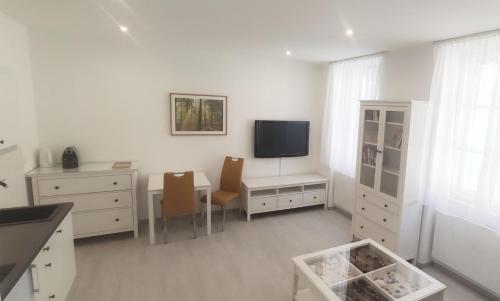 Dieses weiße Zimmer verfügt über einen Schreibtisch und einen TV an der Wand. in der Unterkunft Gemütliche Zweiraumwohnung in Ruhelage in Wien
