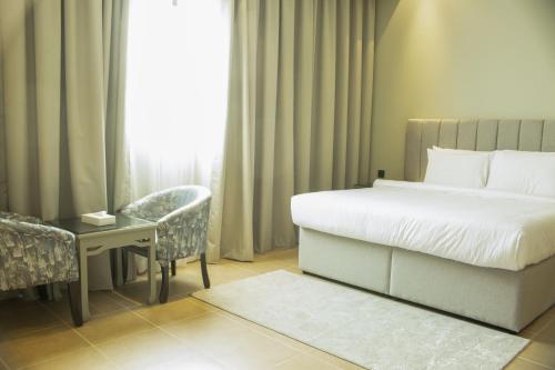 a bedroom with a bed and a desk and a window at Infinity Tower Suites WLL in Manama