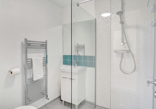 a white bathroom with a shower and a sink at East Dene in Overstrand