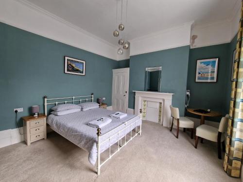a bedroom with blue walls and a bed and a desk at The Portland Hotel in Folkestone