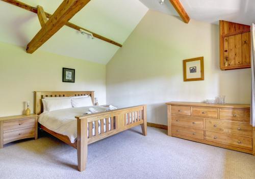 a bedroom with a large bed and a wooden dresser at Farm Cottage in Sidestrand