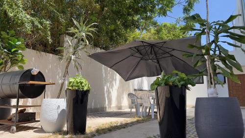 un parasol dans une cour avec des plantes en pot dans l'établissement Cozy Appartement in a Villa close to Mahaj Riad Rabat, à Rabat