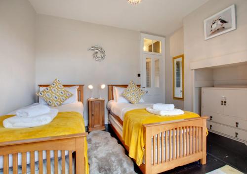 克羅默的住宿－Flat 1 Trent House，一间卧室配有两张带黄床单的床