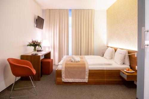 ein Hotelzimmer mit einem Bett und einem Stuhl in der Unterkunft Hotel Engel am Bahnhof in Wädenswil