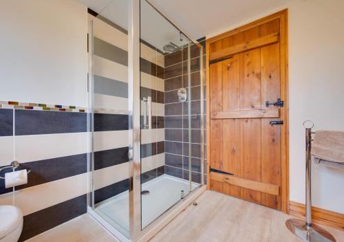 a bathroom with a shower and a glass door at Flaxmans Farmhouse in Roughton