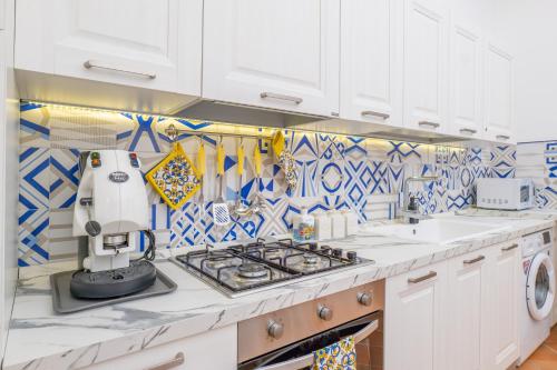 uma cozinha com armários brancos e azulejos azuis e brancos em YourHome - Casa Moscatelli 150 steps em Positano