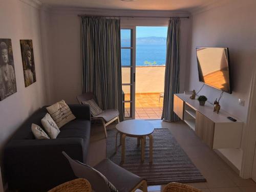 ein Wohnzimmer mit einem Sofa und einem Tisch in der Unterkunft Volcano Beach Views & Wifi in Puerto de Santiago