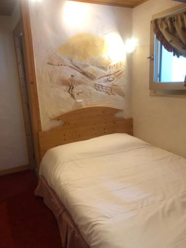 a bed in a room with a painting on the wall at Hôtel la Kinkerne in Morzine