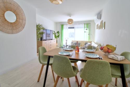 a dining room with a wooden table and green chairs at Center location, AC, swimming pool, and parking in Olhão