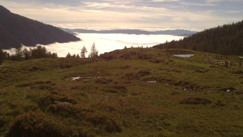 a grassy hill with a view of a valley of clouds at Karnerhof in Mariapfarr