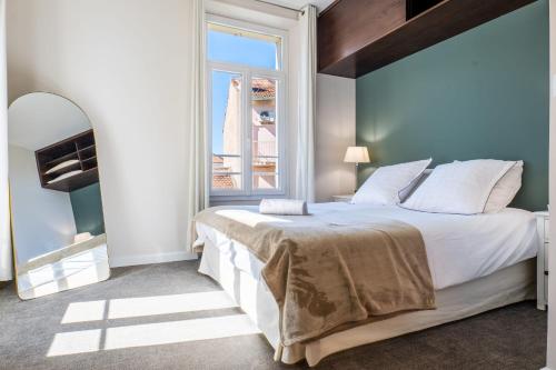 une chambre avec un grand lit et une grande fenêtre dans l'établissement Stylish 1-Bedroom Apartment Near Beaches & Croisette, à Cannes
