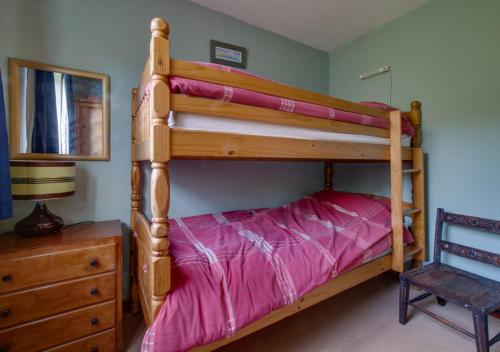 a bedroom with a bunk bed with pink sheets at Happidays in Lessingham