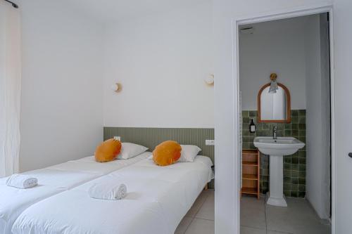 2 bedden met oranje kussens in een kamer met een wastafel bij NOCNOC - Le Ceramica - Le calme en ville, T3 très fonctionnel in Montpellier