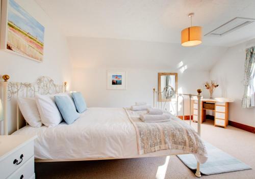 1 dormitorio con cama blanca y almohadas azules en Haven Cottage, en South Walsham
