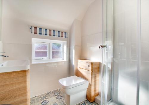 y baño blanco con aseo y ducha. en Haven Cottage, en South Walsham