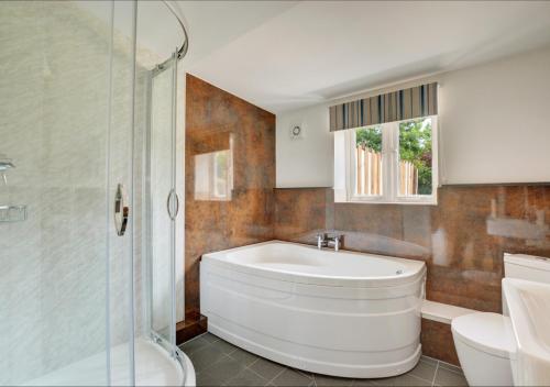 uma casa de banho com uma banheira, um chuveiro e um WC. em Hawthorn Cottage 