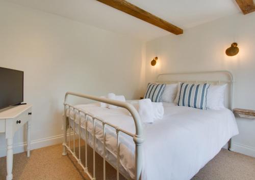 a bedroom with a bed and a flat screen tv at Holly Cottage in Holt