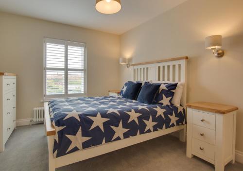 霍爾特的住宿－Holly Tree Cottage，一间卧室配有一张带蓝色和白色棉被的床