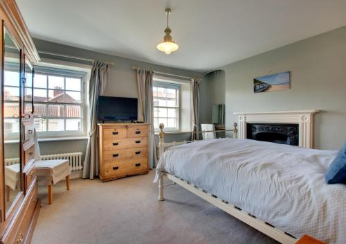 a bedroom with a bed and a television and a fireplace at Holly Cottage in Cromer