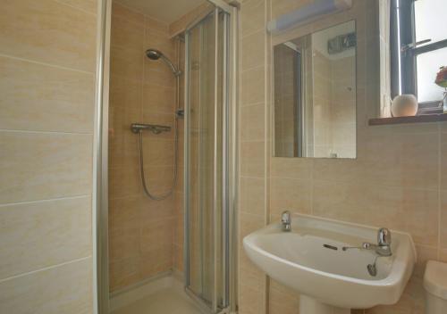 a bathroom with a shower and a sink and a sink at Holly Cottage in Banningham