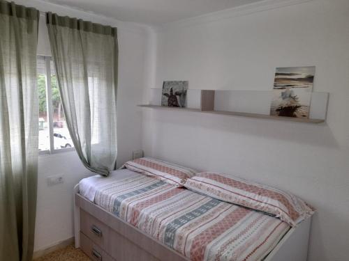 Dormitorio pequeño con cama y ventana en Las Dunas en El Puerto de Santa María
