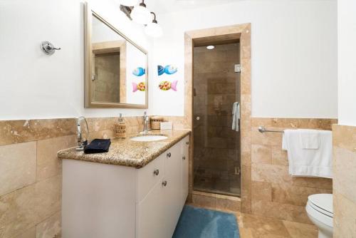 a bathroom with a sink and a toilet and a shower at The Cottonwood House - Beach Villa in Providenciales