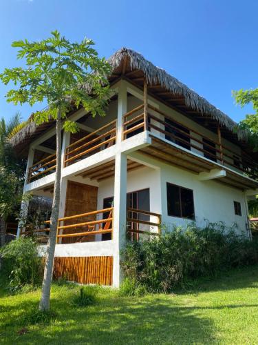a white house with a thatched roof at Hosteria Guachapeli in Las Tunas