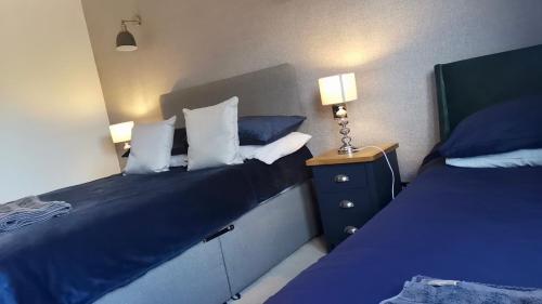a bedroom with two beds and a night stand with two lamps at Tanera in Inverness