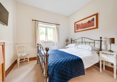 um quarto com uma cama com um cobertor azul em Keepers Cottage em East Dereham