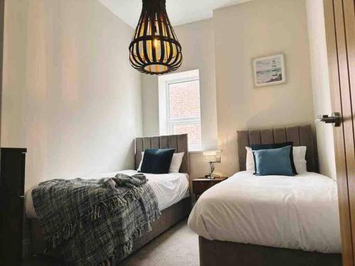 a bedroom with two beds and a chandelier at The Old Station House by Holiday Heim in Lytham St Annes