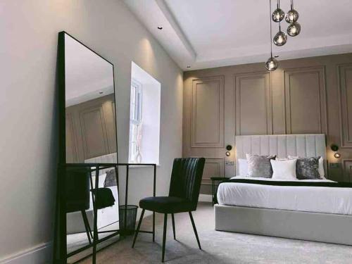 a bedroom with a bed and a mirror and a chair at The Old Station House by Holiday Heim in Lytham St Annes
