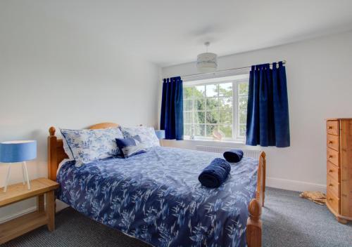 a bedroom with a bed with blue sheets and a window at Laburnum House in King's Lynn