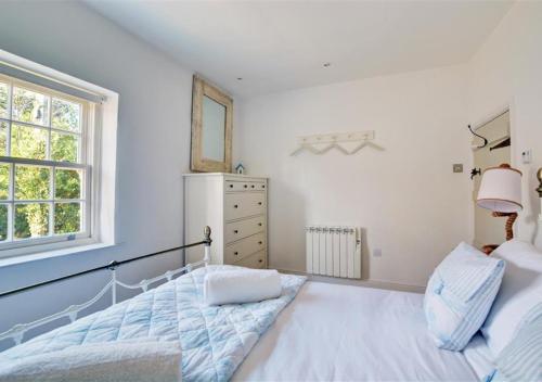 a white bedroom with a bed and a window at Lavender Cottage in North Creake