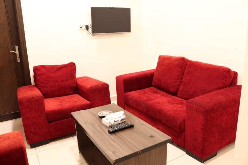 2 rote Stühle und ein Tisch in einem Zimmer in der Unterkunft Future 2 Hotel Apartments in Aqaba