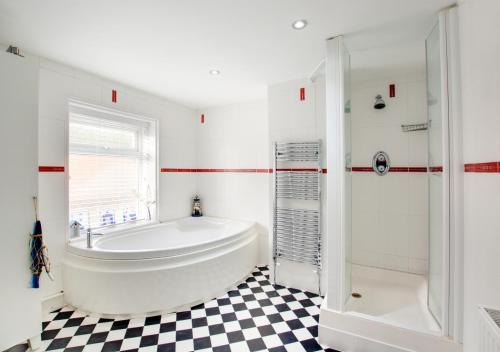 a white bathroom with a tub and a shower at Larkrise in West Runton