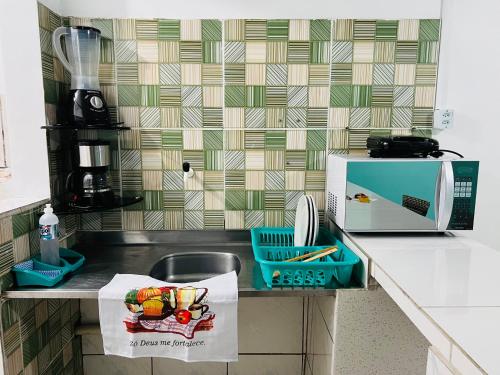 encimera de cocina con fregadero y microondas en La casita Verde, en Beberibe