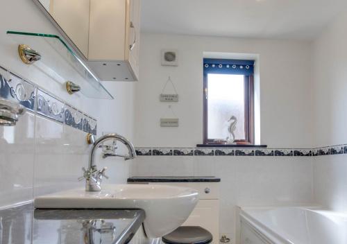 a white bathroom with a sink and a window at Lays Barn in Rockland Saint Peter