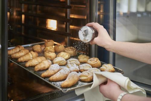 a person is making donuts in an oven at Frühstückshotel Birkenhof in Rauris