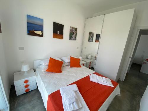a bedroom with a white bed with orange pillows at Verde Oliva Residence in Ispica