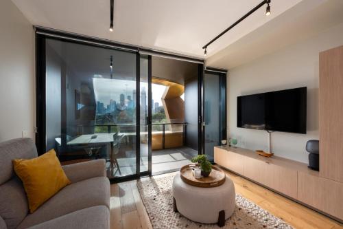 ein Wohnzimmer mit einem Sofa und einem TV in der Unterkunft 2-Bed in South Melbourne w Beautiful City Views in Melbourne