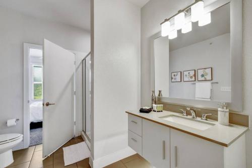 Un baño blanco con lavabo y espejo. en Charming Apartment in Southtown Wifi Pool Gym, en San Antonio