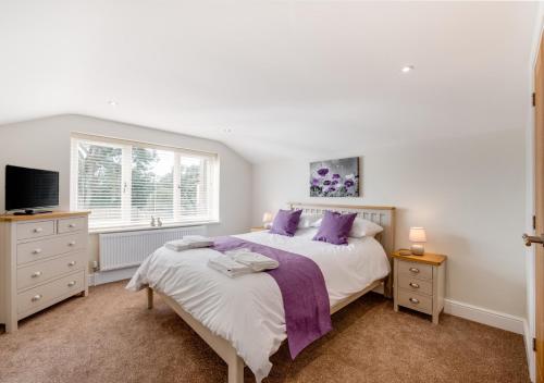 a bedroom with a large bed with purple pillows at Lillie Cottage in Brisley
